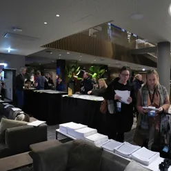 Personer som står foran programmer på konferanse