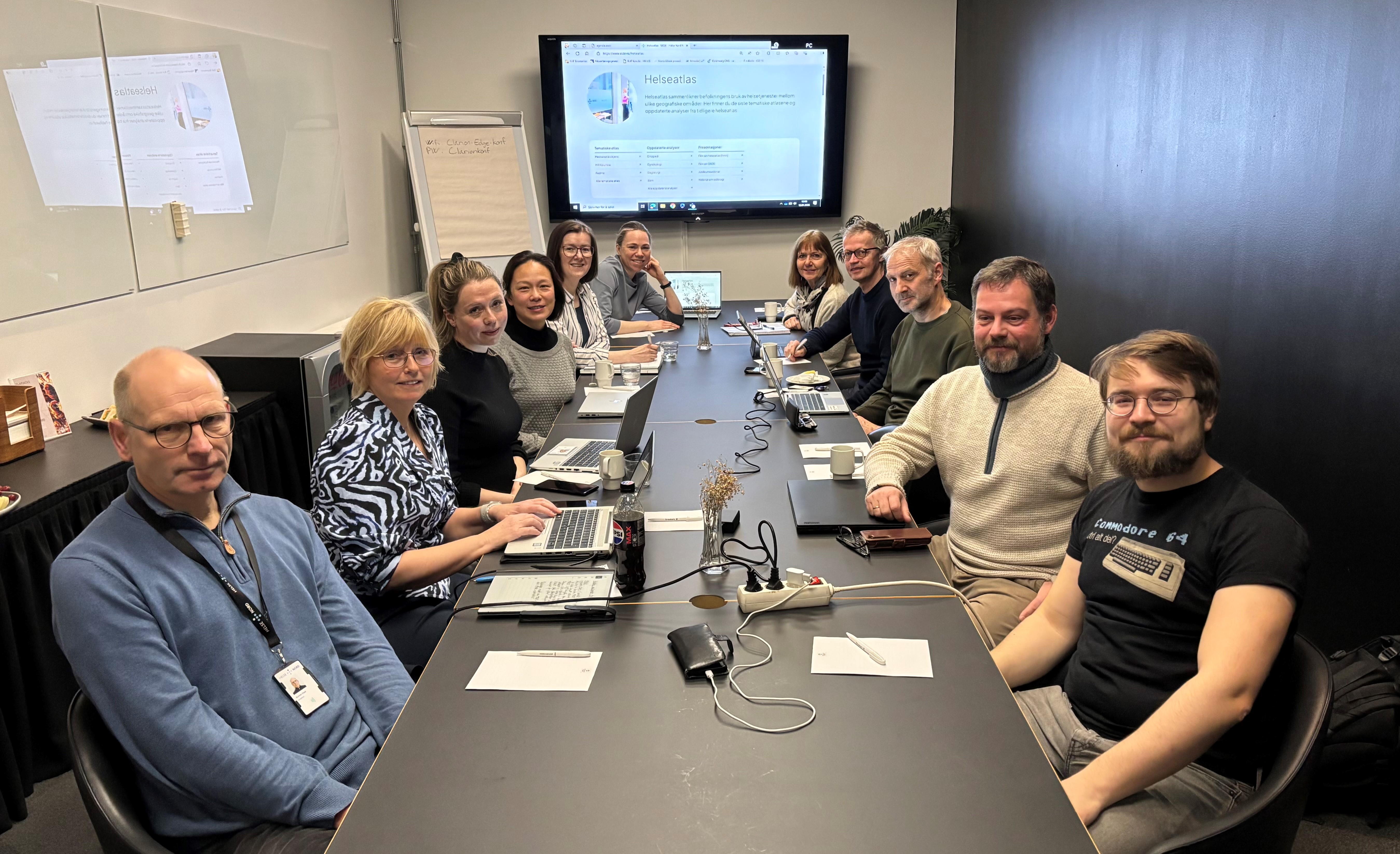 En gruppe mennesker som sitter rundt et bord med datamaskiner