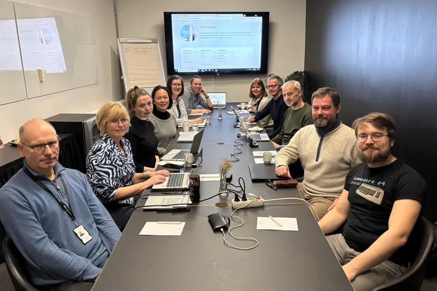 En gruppe mennesker som sitter rundt et bord med datamaskiner