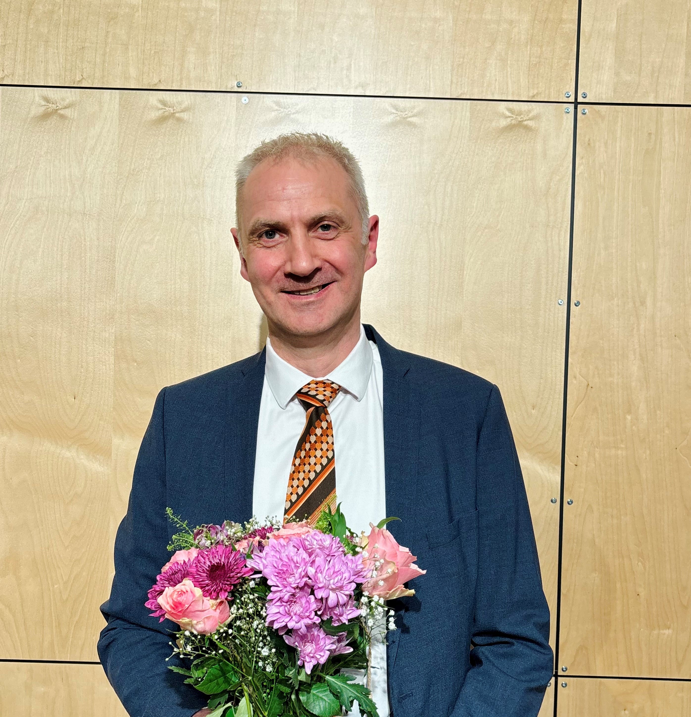 En mann i dress som holder en bukett blomster